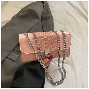 Close-up of pink faux leather crossbody bag with snake skin pattern and silver chain strap