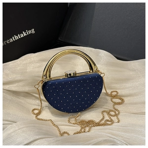 Détail de la pochette boîte en acrylique bleu marine avec poignée ronde dorée et pois