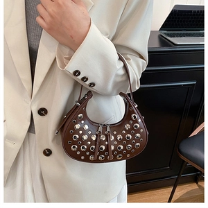 Detail of studded dark brown crescent shoulder bag with silver rivets and dual zippers