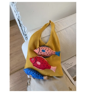 Gros plan d'un sac cabas en tricot jaune avec trois breloques poissons en peluche
