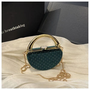 Détail de pochette en velours vert foncé avec clous dorés et poignée anneau