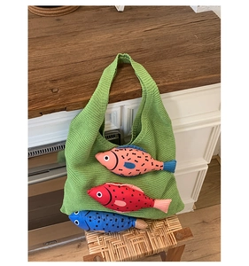 Détail du sac tricoté vert avec trois breloques de poissons en tissu 3D fait main
