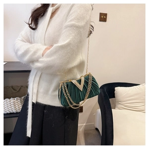 Détail d'une pochette de soirée en velours vert émeraude plissé avec boucle en strass en V