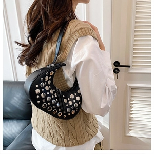 Detail of black crescent shoulder bag featuring silver rivets and high-quality leather texture