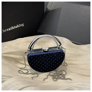 Détail d'un sac de soirée en velours bleu marine avec rivets et poignée argentée