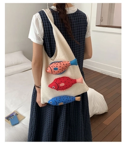 Close-up of cream knit tote bag featuring colorful 3D fish decorations and soft texture