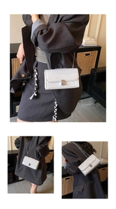 Close-up of white crocodile pattern PU leather with silver chain strap and metal clasp