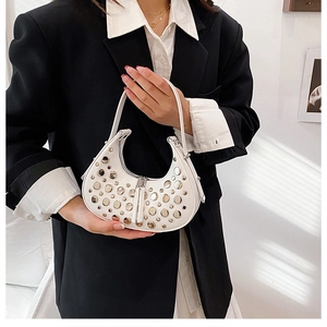 Close-up of white hobo bag with silver studs and leather tassels held by a model