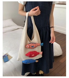 Detail of knit handbag featuring three colorful stuffed cartoon fish on cream texture