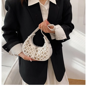 Close-up of white crescent bag with mixed metal studs and secure zipper closure