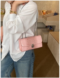 Close-up of pink faux leather bag with crocodile pattern and silver chain strap