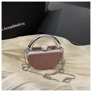 Gros plan sur la pochette en velours rose avec strass et poignée métallique ronde