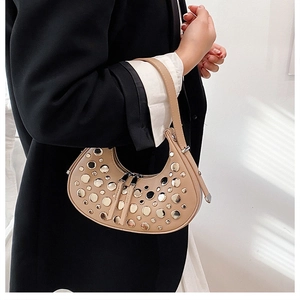 Close-up of beige leather crescent bag with silver rivet details worn by model