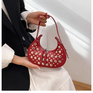 Detail of red crescent bag with silver rivets and dual zipper on model with black blazer