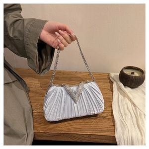 Détail d'un sac de soirée plissé scintillant avec boucle argentée en V sertie de strass