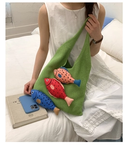 Détail du sac cabas en tricot vert avec trois charms poissons colorés en situation de vie