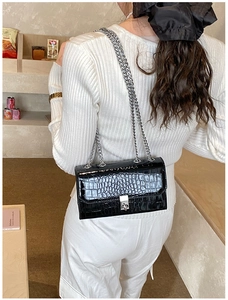 Close-up of black crocodile pattern PU leather shoulder bag with silver chain strap