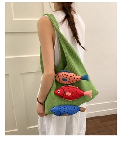 Detail of green knitted tote bag with colorful cartoon fish ornaments and textured weave
