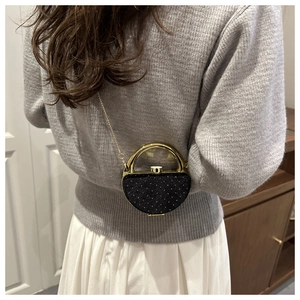 Détail d'un mini sac de soirée noir pailleté avec poignée dorée et bandoulière chaîne