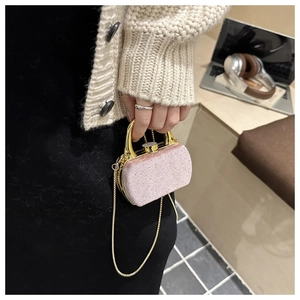 Mini sac boîte à paillettes roses avec poignée dorée tenu par un mannequin