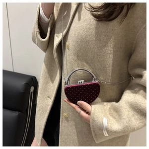 Détail de la pochette coeur en velours bordeaux avec strass et poignée en métal