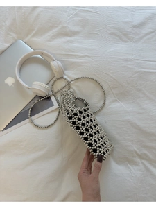 Gros plan d'un sac en perles argentées fait main avec doublure noire et bandoulière perle