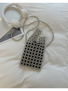 Sac à perles argenté avec poignées tressées et pochette noire sur un décor minimaliste
