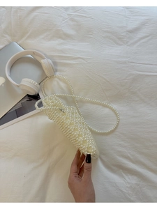 Détail du sac à bandoulière en perles blanches tissées à la main sur surface blanche