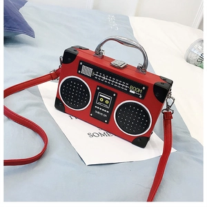 Détail du sac à main radio vintage rouge avec poignée métallique sur lit bleu
