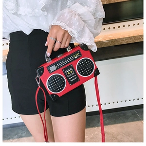 Détail du sac à main rouge vintage en forme de radio avec poignée métallique et motif haut-parleur