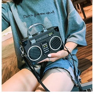 Détail du sac bandoulière rétro en forme de radio, cuir noir texturé et poignée métallique