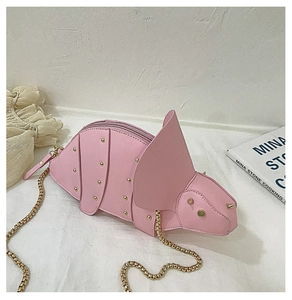 Détail du sac dinosaure rose en cuir avec clous dorés et bandoulière en chaîne