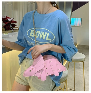Vue latérale du sac bandoulière dinosaure rose avec clous dorés et chaîne sur modèle