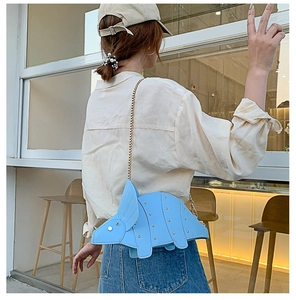 Détail du sac tricératops bleu clair avec rivets dorés et chaîne sur un mannequin