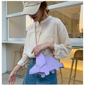 Détail du sac tricératops violet avec rivets dorés et bandoulière sur mannequin