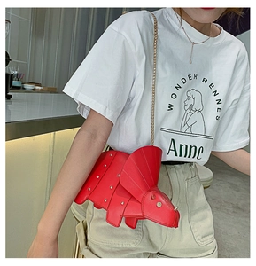 Détail du sac dinosaure rouge avec rivets argentés et bandoulière chaîne dorée