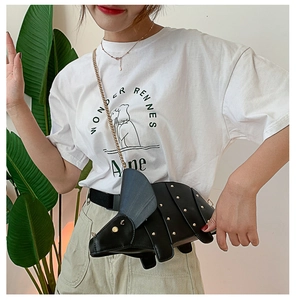 Détail d'un sac créatif noir en forme de dinosaure avec rivets dorés et bandoulière chaîne
