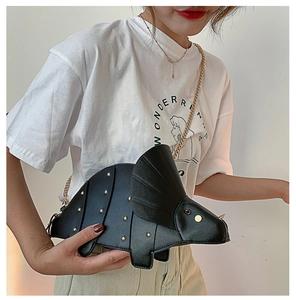Détail du sac tricératops noir créatif avec clous dorés et bandoulière porté par un mannequin