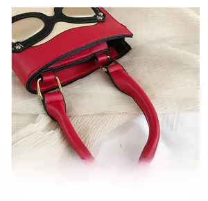 Détail d'un sac à main rouge en PU avec poignée cylindrique et boucles dorées en D