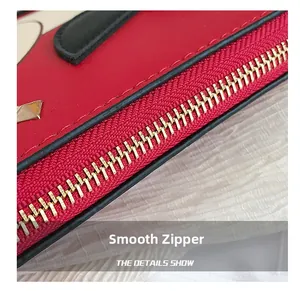 Détail macro d'une fermeture éclair dorée lisse sur un sac en cuir rouge grainé