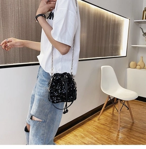 Detail of black sequin bucket bag with silver chain strap and drawstring closure
