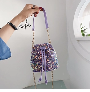Detail of purple sequin bucket bag with drawstring closure and golden chain strap