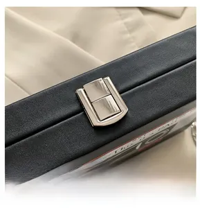 Détail du fermoir argenté sur sac en cuir grainé noir avec texte Romantic Mix