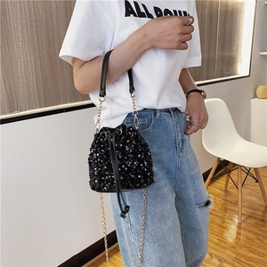 Sparkly black sequin bucket bag with drawstring closure and golden chain shoulder strap