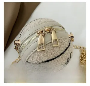 Dettaglio della doppia cerniera dorata sulla mini borsa in pile sherpa color panna