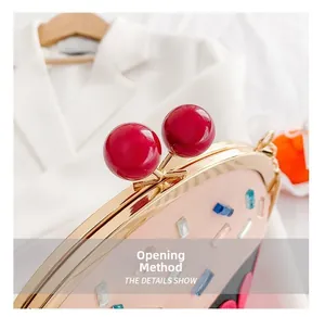 Detail showing the cherry-shaped red sphere clasp on a pink designer cake handbag