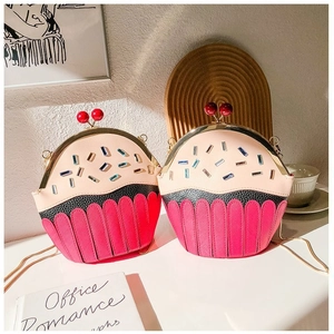 Detail of cupcake-shaped crossbody bag with cherry clasp and golden chain strap