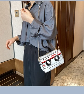 Detailed view of white vintage cassette tape crossbody bag with gold chain strap on model