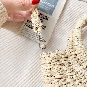 Detail of high-quality silver metal hook on hand-woven straw shoulder bag with buckle