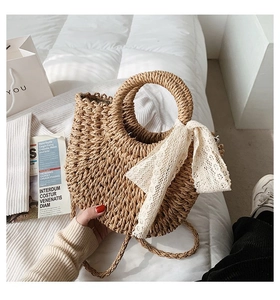 Detailed close-up of handmade straw bucket bag with elegant white lace ribbon on handles